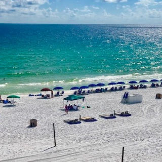 Beach chairs and colorful umbrellas lining a white sand beach beside turquoise water.