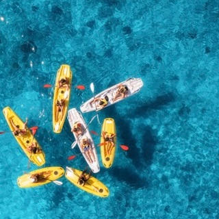Aerial view of kayakers paddling in clear turquoise water.
